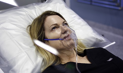 A patient relaxes in a hyperbaric oxygen chamber. The mask she is wearing is supplying her with pure oxygen.